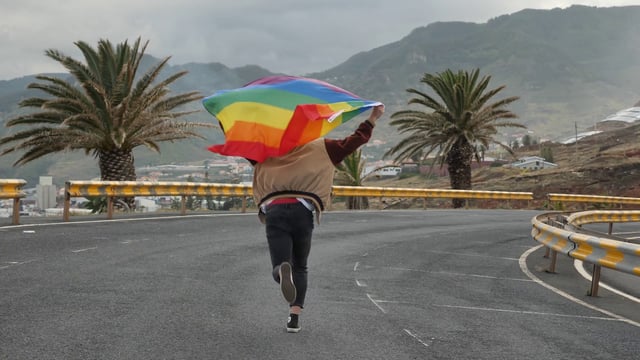 Running & Holding Pride Flag on Street